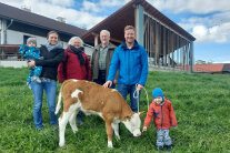 6 Personen stehen hinter einem Kalb