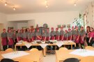 Große Gruppe von Persopnen, meist Frauen, überwiegend in grau-violetter Kleidung, steht in Reihe vor Buffett.