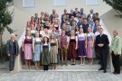 Mehrere Reihen von Personen, zu Gruppenbild aufgestellt, die festlich gekleidet sind.
