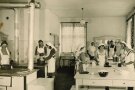 Historisches Bild der Schulküche, in der viele Frauen kochen und backen.
