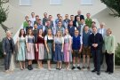 Mehrere Reihen von Personen, zu Gruppenbild aufgestellt, die festlich gekleidet sind.