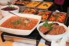 Schüsseln mit schmackhaften Speisen und Beilagen auf Buffetttisch.