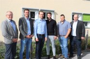 Gruppe von sechs Personen im Freien vor Gebäude.