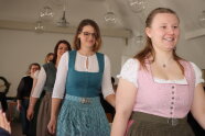 Jüngere Frauen marschieren in einer Reihe in selbst hergestellten Dirndln an Publikum vorbei.