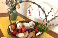 Körbchen mit Palmzweigen, Kerze, Osterlamm und Eiern.
