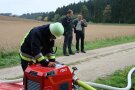 Feuerwehrmann an technischem Gerät, dahinter zwei Mitarbeiter des Forstbereiche des Amtes.