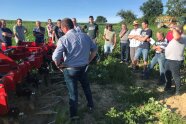 Landwirt und Maschine auf Feld vor Zuhörergruppe.